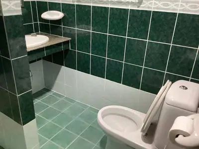 a green tiled bathroom with a toilet and a sink at Freedom house in Karon Beach