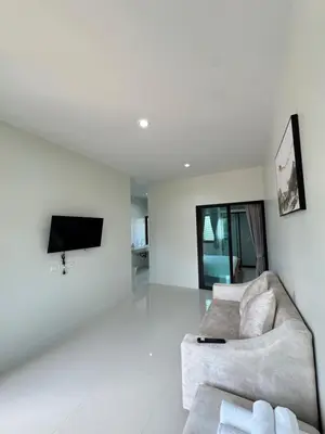 a white living room with a couch and a tv at Lela Home in Phuket Town