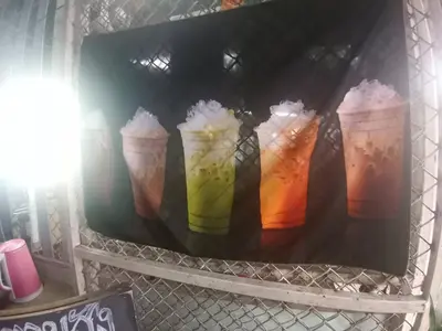 a shelf with four different colored drinks in cups at Come see comsa in Koh Lone