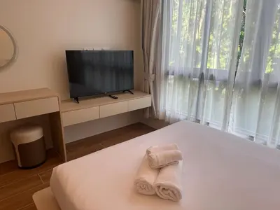 a bedroom with a bed with a television and towels at Kamala Apartments in Kamala Beach