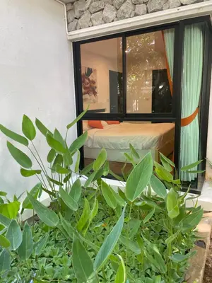 a room with a bed and a window with green plants at Rawai Title 3 in Rawai Beach