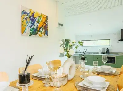 a dining room table with a vase of flowers on it at Wink Garden 3 Bedrooms Bangtao Beach Phuket in Ban Thalat Choeng Thale