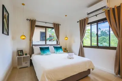 a bedroom with a large bed with blue pillows at Wink Garden 3 Bedrooms Bangtao Beach Phuket in Ban Thalat Choeng Thale