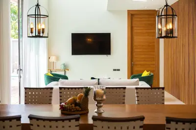 a dining room with a table and a couch at Teak 5 BR Pool Villa Bang Tao Airport Shuttle in Laguna Phuket