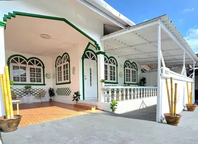 a white and green house with a porch at Village Beach House I in Patong Beach