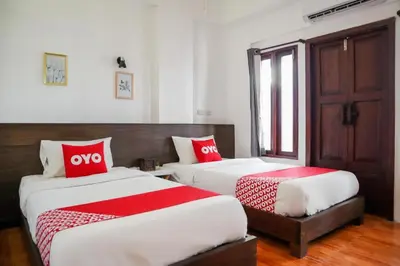 two beds in a room with red and white pillows at OYO 778 21 Poshtel in Phuket Town