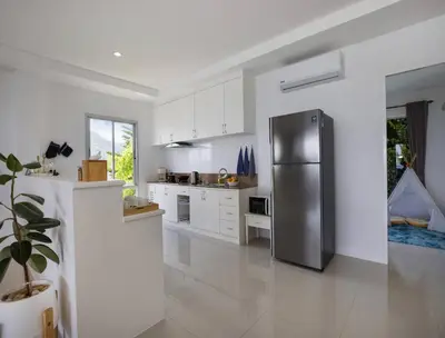 a kitchen with a stainless steel refrigerator and white cabinets at Oceanview Kata Penthouse - Pasifora in Kata Beach