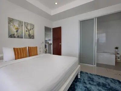 a white bedroom with a large bed and a large window at Oceanview Kata Penthouse - Pasifora in Kata Beach