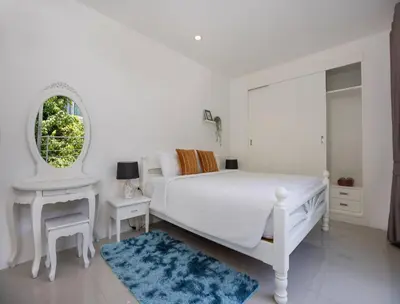 a white bedroom with a white bed and a mirror at Oceanview Kata Penthouse - Pasifora in Kata Beach