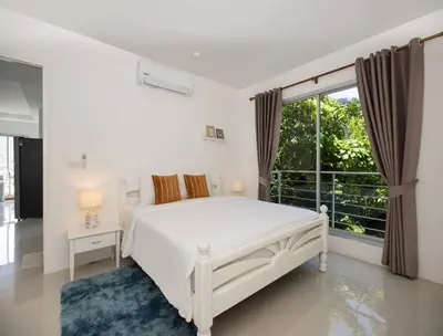 a white bedroom with a bed and a large window at Oceanview Kata Penthouse - Pasifora in Kata Beach