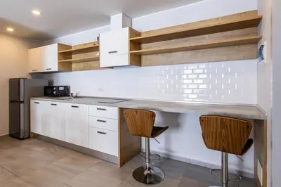 a kitchen with white cabinets and two bar stools at Pool View 1 Bed Apt T2-720 in Chalong