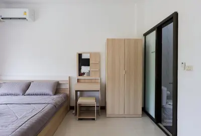 a bedroom with a bed and a desk and a chair at StayKa Suites in Karon Beach