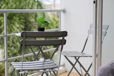 a black chair and a plant on a balcony at StayKa Suites in Karon Beach
