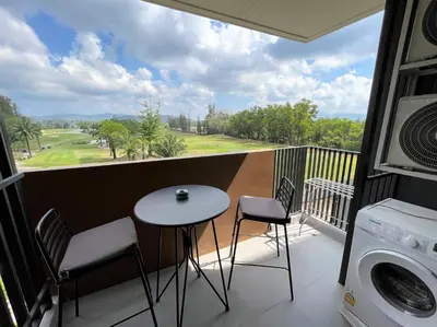 a balcony with a table and chairs and a view of a golf course at Apartment at Skypark Laguna next to golf course in Bang Tao Beach