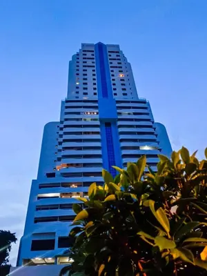 a tall blue building with trees in front of it at Patong Tower in Patong Beach