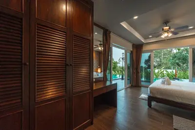 a bedroom with a bed and a large wooden closet at V269 Yamu Sunset Villa 3BR Sea View Pool Retreat in Ban Bang La
