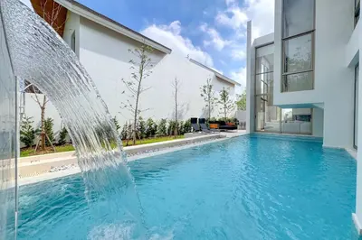 a pool with a water fountain in front of a house at Designer 3BR Pool Villa in New Build LuxPride 4 L8 Residence in Bang Tao Beach