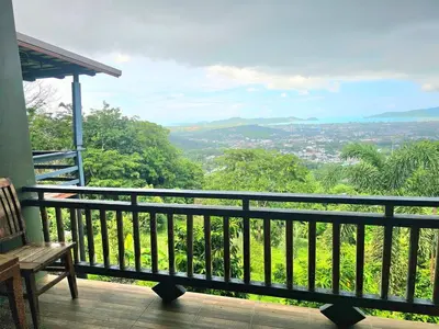 a balcony with a bench and a view of a city at The house on the hill in Ban Na Kok