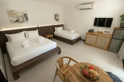 a room with two beds and a table and a television at Green Garden Villa Hotel in Nai Harn Beach