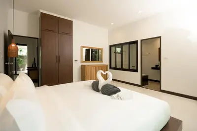 a bedroom with a white bed with a swan on it at Green Garden Villa Hotel in Nai Harn Beach