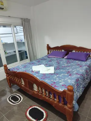 a bedroom with a wooden bed with purple pillows at Maison local avec terrasse et cuisine extérieure Proche Patong in Kathu
