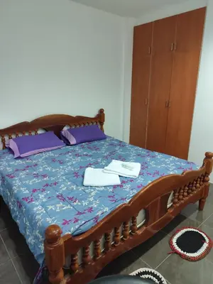 a bedroom with a wooden bed with purple pillows at Maison local avec terrasse et cuisine extérieure Proche Patong in Kathu