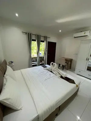 a large white bed in a room with a window at J&B House in Nai Yang Beach