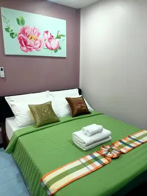 a bedroom with a large bed with a green blanket at 9 Home Phuket in Ban Rangeng