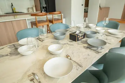 a table with white plates and wine glasses on it at Mouana Breeze Maikhao 3-bedroom Pool Villa 9917 in Mai Khao Beach