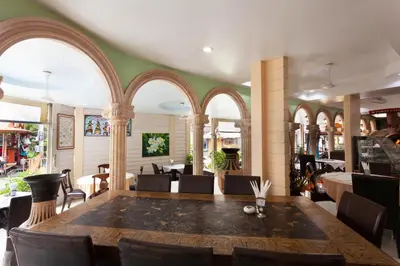 a restaurant with a large wooden table and chairs at Da Mario Hotel & Restaurant in Karon Beach