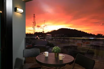 a table on a balcony with a sunset in the background at 1bdr Modern Apartment Cozy Seaview Stay in Surin Beach