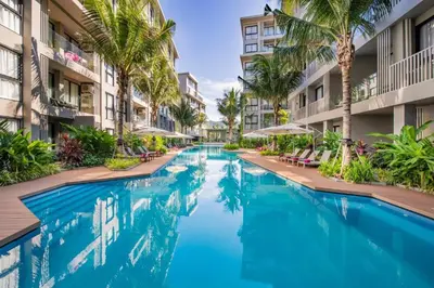 a swimming pool in the middle of a building with palm trees at Apartment Diamond Resort BangTao in Bang Tao Beach