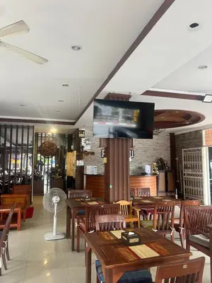 a restaurant with wooden tables and a flat screen tv at SK Residence And Restaurant Patong in Patong Beach