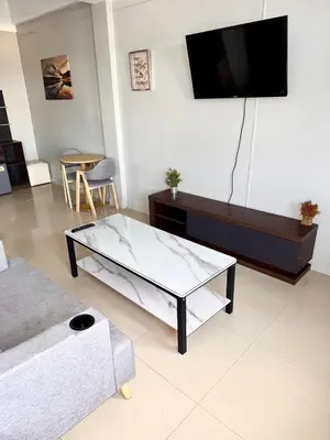 a living room with a glass coffee table and a tv at Green Terrace Residence Phuket in Kathu