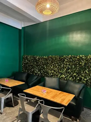 a green wall with two tables and chairs at Green Terrace Residence Phuket in Kathu