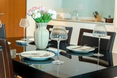 a dining room table with a vase of flowers and wine glasses at Patong private spacious apart-ment 2 minutes walk to the beach bathtub sea view swimming pool in Patong Beach