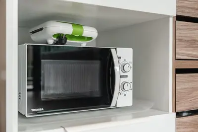 a microwave with a phone on top of it at C188 Modern Condo Pool Gym & Walk to Rawai Beach in Rawai Beach