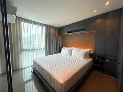 a bedroom with a bed and a large window at C191 CityGate Kamala Stylish Stay by Pools and Gym in Kamala Beach