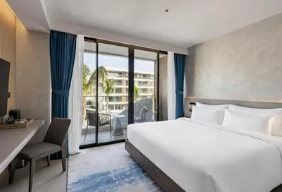 a hotel room with a large bed and a balcony at Sunshine Beach Residence Resort in Phuket Town