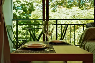 a table with a wine glass and plates on a balcony at Cozy New 1-Bedroom Apartment with Pool, 5 Min Walk to Kamala Beach in Kamala Beach