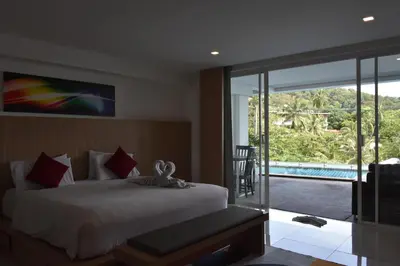a bedroom with a bed and a view of a pool at Lae Lay Suite in Karon Beach