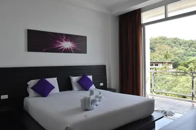 a bedroom with a bed and a large window at Lae Lay Suite in Karon Beach