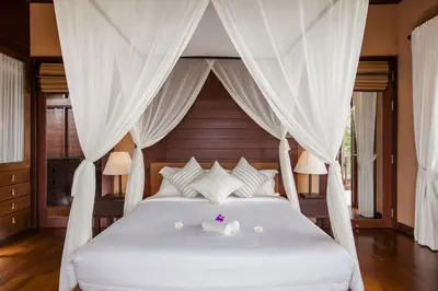 a bedroom with a white bed with white drapes at Villa Lydia, Koh Yao Noi in Ko Yao Noi