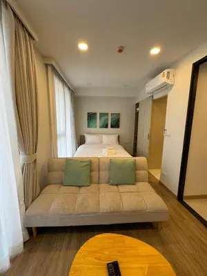 a living room with a couch in front of a bed at Cozy studio Laguna SkyPark Phuket in Laguna Phuket
