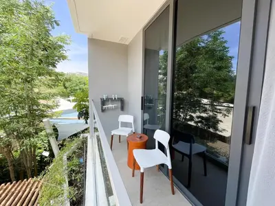 a balcony with white chairs and a view of the street at Layan Green Residence by ShowProperty in Layan Beach