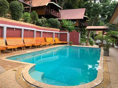 a swimming pool with orange chairs next to a building at Phi Phi Ingphu Viewpoint Hotel in Phi Phi Don