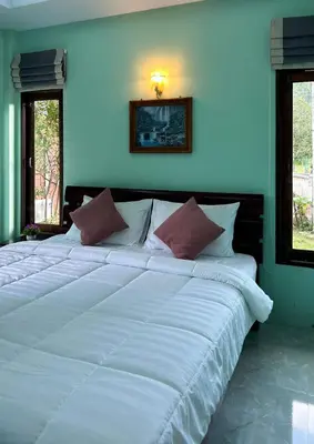 a large white bed in a room with two windows at Sun-San Thalane Resort in Ban Laem
