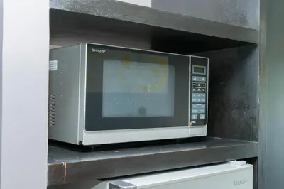 a microwave oven sitting on top of a shelf at Beachfront 1 BR Hotel Infinity Pool Patong Phuket in Patong Beach