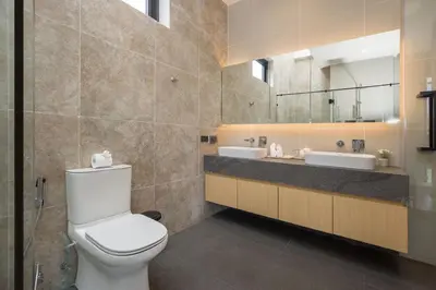 a bathroom with a toilet and two sinks and a mirror at Chalong Bay View 3BR Pool Villa Long One B10 in Chalong