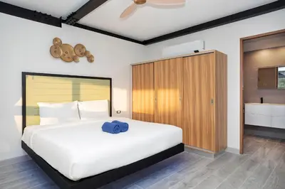 a bedroom with a large white bed and a wooden cabinet at New 2-Storey Villa Sunset Garden 8 with 4BR & Eco-Pool, near Naiharn in Rawai Beach